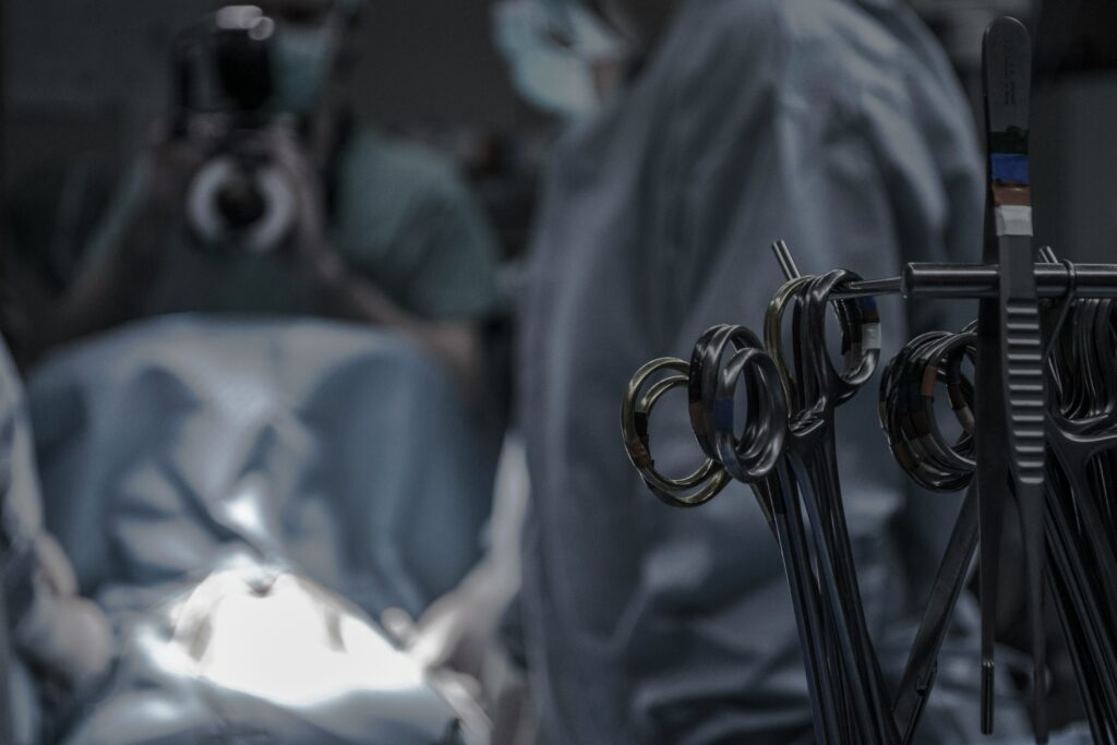 Close-up of surgical scissors in an operating room illustrating the application of AI in healthcare, with surgeons in the background.